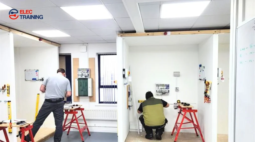 Adult learners carrying out hands-on electrical training in individual work bays at an Elec Training facility.